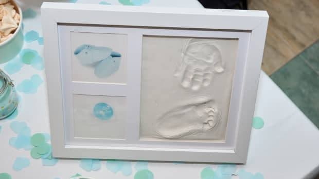 Baby footprint and handprint on clay mold plaque in a frame. To remember in the future how small the baby was. Cute frame images cheerful childhood celebration event. Baby DIY keepsake to keep forever