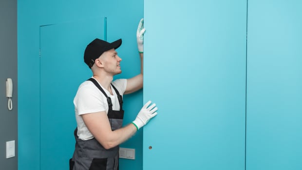 Working male fitter installs hidden invisible installation doors for painting.