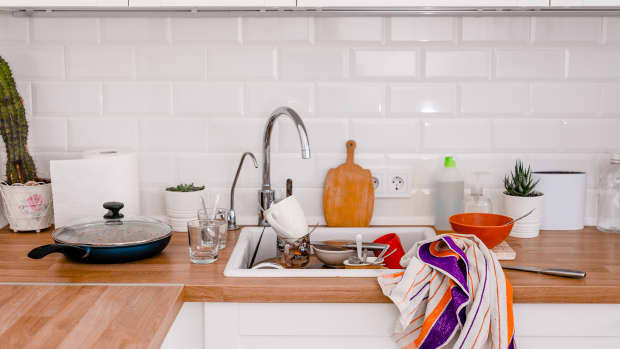 Clutter, dirty dishes by the sink in the white kitchen.