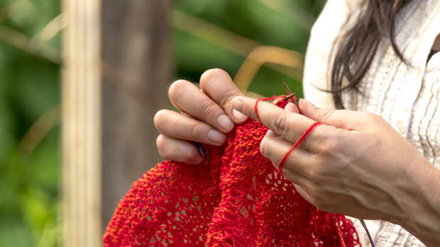 woman knitting something with red yarn