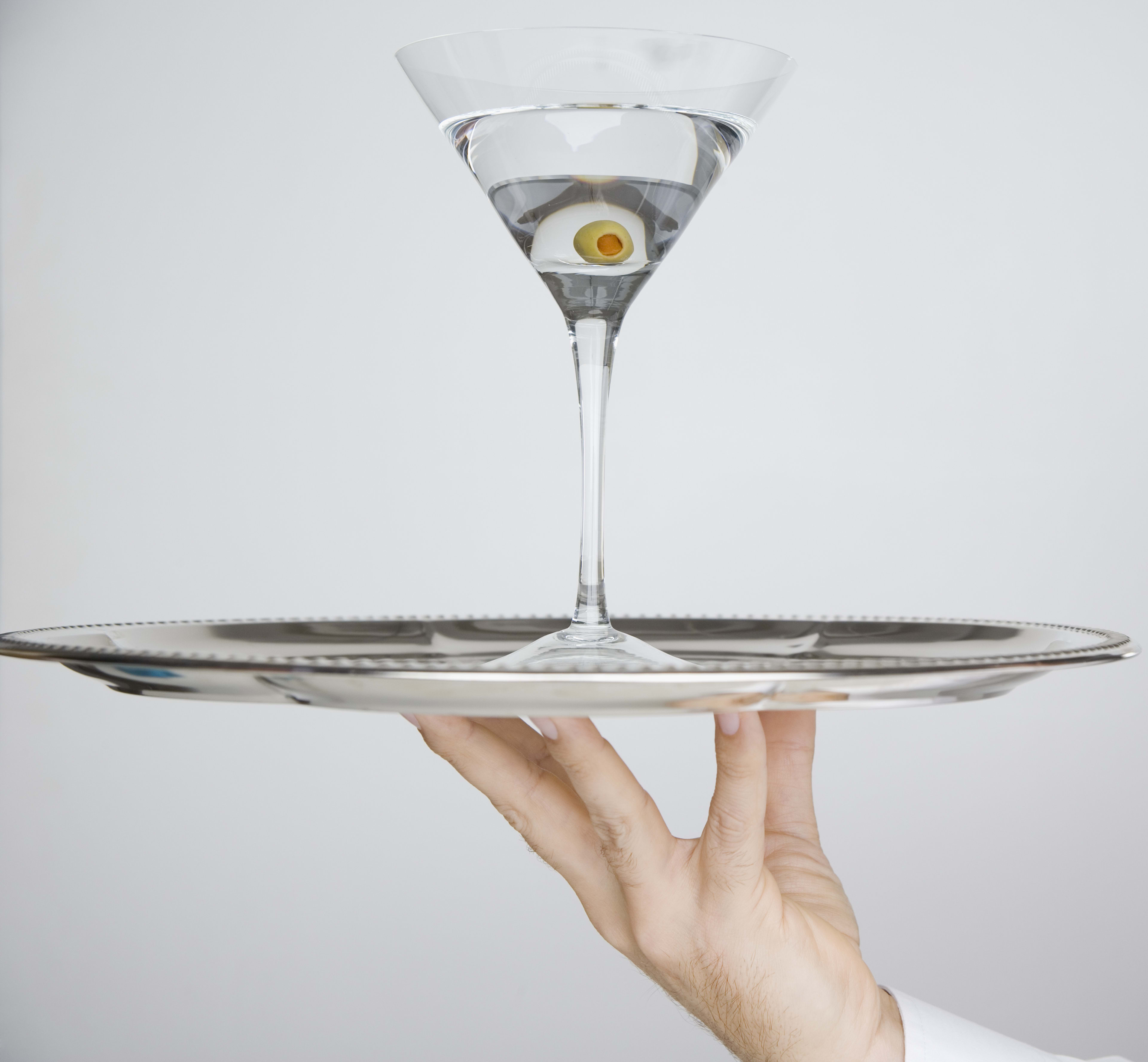 Person holding martini on cocktail tray